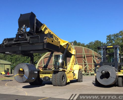 Coil boom spreader attachment for reach stacker.